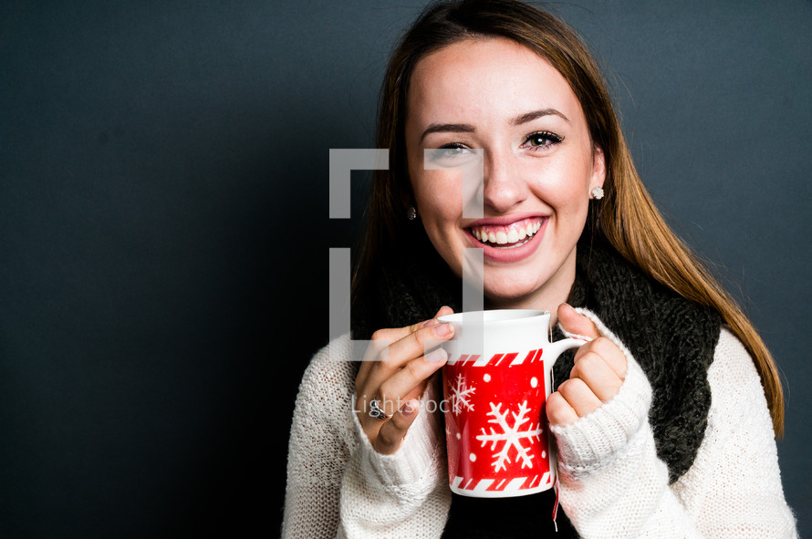 a smiling young woman holding a mug 