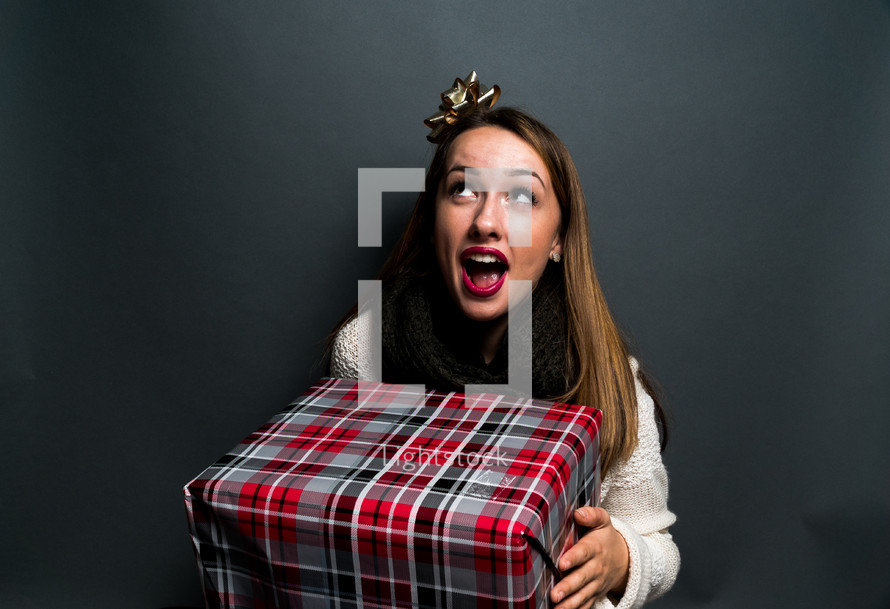 a teen girl holding a wrapped Christmas gift 