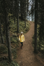 a woman walking on a path through a forest 