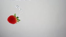 Strawberry droping into water - copy space left