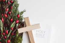 Bible, cross, and branch with red berries on a white background