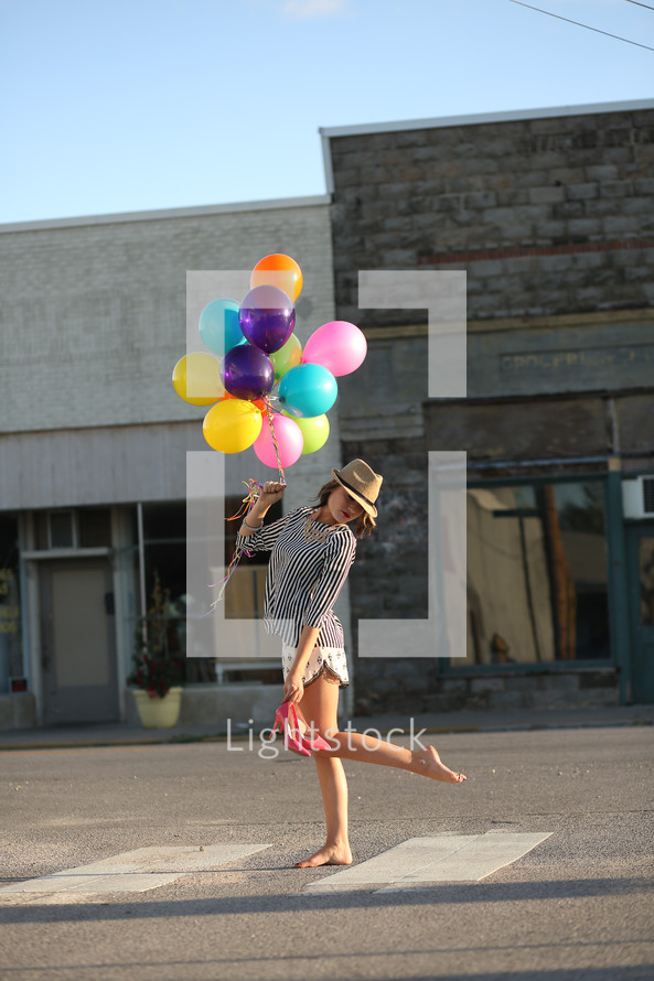 teen girl carrying balloons and her shoes 