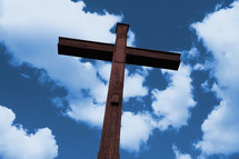 cross of brown wood against white clouds in blue sky