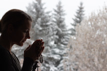 a woman praying with a rosary 