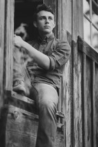 young man sitting in a barn window 