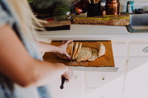 a woman slicing bread with a knife 