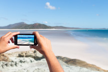 taking a picture with a cellphone on a beach 