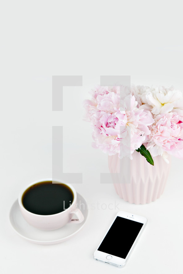 vase of pink flowers, coffee cup, and iPhone 