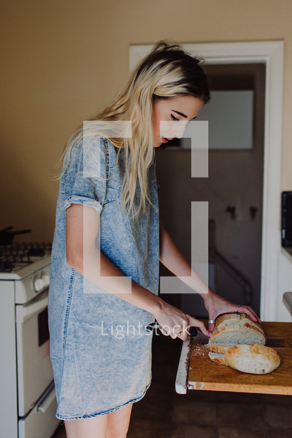 a woman slicing bread in a kitchen 