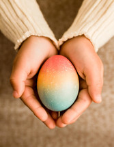 Young childs' hands holding a single colored easter egg for the holiday.