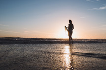 young woman walking on wet sand on a beach at sunset 