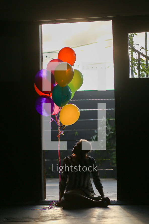 a teen girl sitting on the floor with balloons 