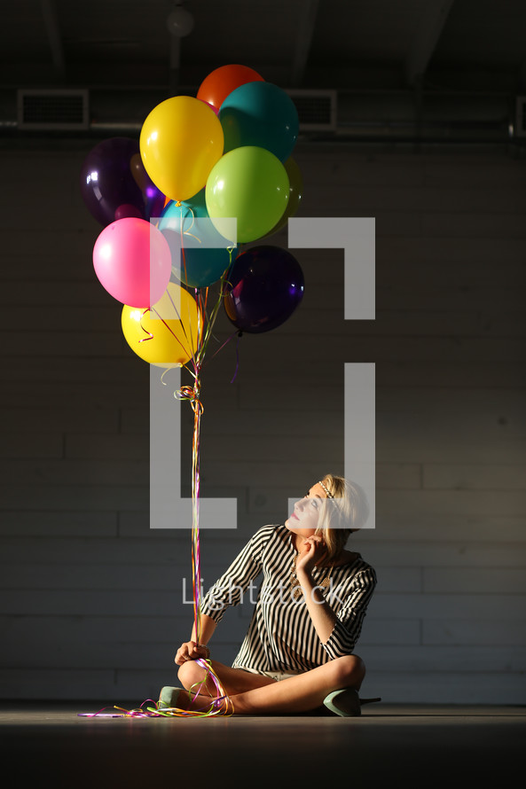 a teen girl sitting on the floor with balloons 