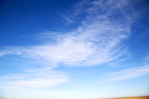 white clouds in a blue sky above a desert 