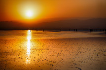 people walking across a salt lake at sunset 