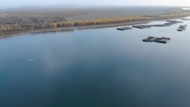 Aerial View Of The Ships Sailing On Danube River Near The Riverside With Lush Forest. 