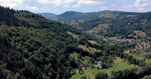 Rural Village At The Valley With Lush Green Forest Of The Mountain Range. aerial