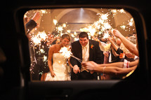 people holding sparklers over a bride and groom as the leave for their honeymoon