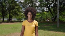 portrait of confident young black woman at the park looking serious at camera independent african american female in outdoors background slow motion

