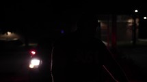 Silhouette of a criminal man in front of flashing police officer, cop car lights of law enforcement officer.