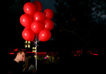man and woman kissing under red balloons