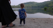 Mother and toddler daughter looking out into lake during summer morning