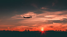 Silhouette of a commercial airplane taking off at sunset.