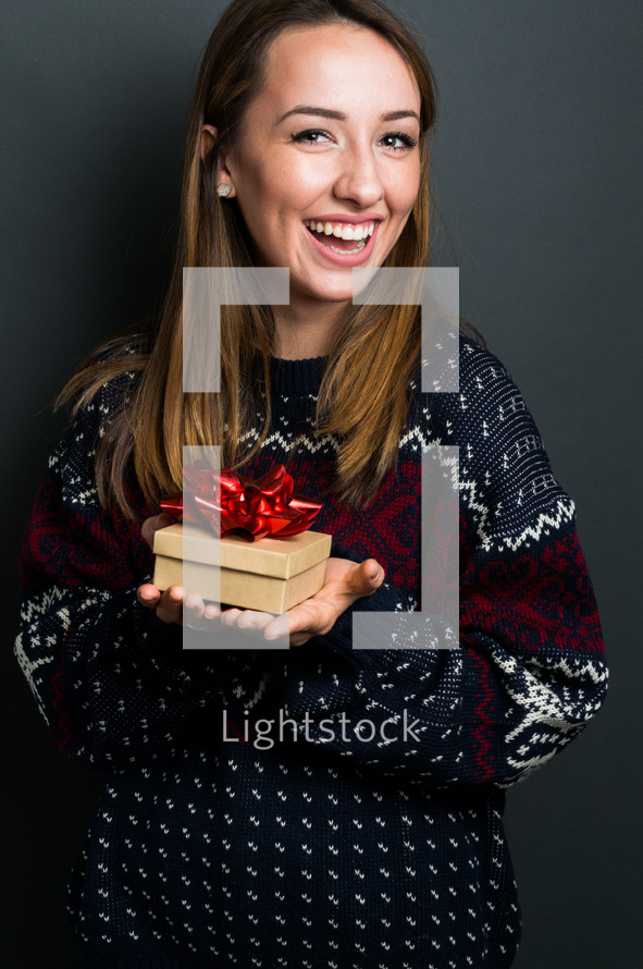 a smiling young woman holding a Christmas gift 