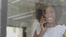 Closeup positive black business woman talking smartphone in office interior. Smiling businesswoman calling mobile phone in Slow motion 
