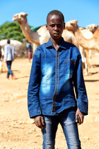 a young boy standing in a market near camels in Ethiopia 