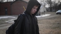 Young man, teenager with backpack and winter coat walking. A young, teen boy walking to high school or young homeless man. 