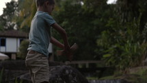 Young boy taking paper boat out of water  on stream - medium shot