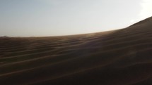 Middle eastern desert, nature landscape. Sand blowing in wind over desert sand dunes in evening desert sunset, sunlight in cinematic slow motion.