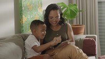 Latina mother and son spending time together playing on a tablet