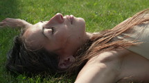 Woman laying in grass eyes closed relaxing - close up on face