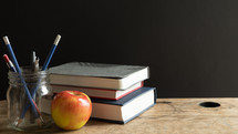 apple, books, and pens on a desk 