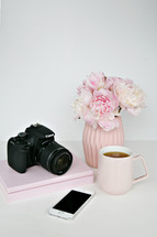 vase of flowers, camera, phone, coffee mug, and books 