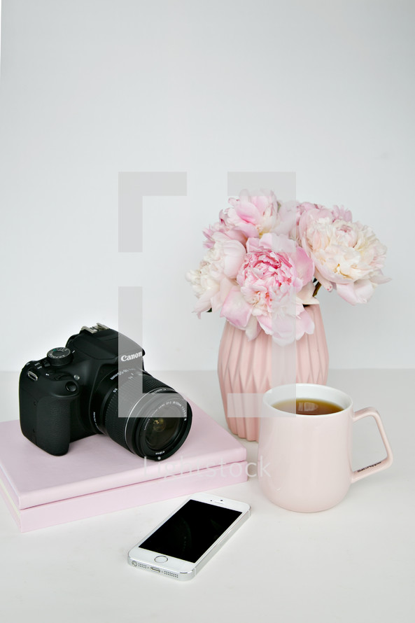 vase of flowers, camera, phone, coffee mug, and books 