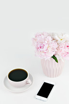 vase of pink flowers, coffee cup, and iPhone 