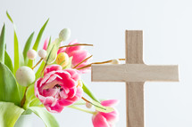 Pink flowers with Easter egg decoration and wooden cross