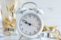 gold streamers and alarm clock on a white background