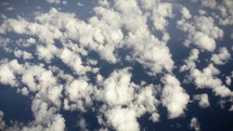 View of earth, ocean and clouds from airplane window while flying in cinematic slow motion.