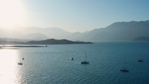 Aerial shot of beautiful lake with ships cruising on cloudless day, water surface reflecting sunshine, mountains and sky in the background. Potrerillos Dam located in Argentina
