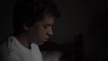 Sad, depressed, anxious young man. A grieving teenager sitting alone in his bedroom.