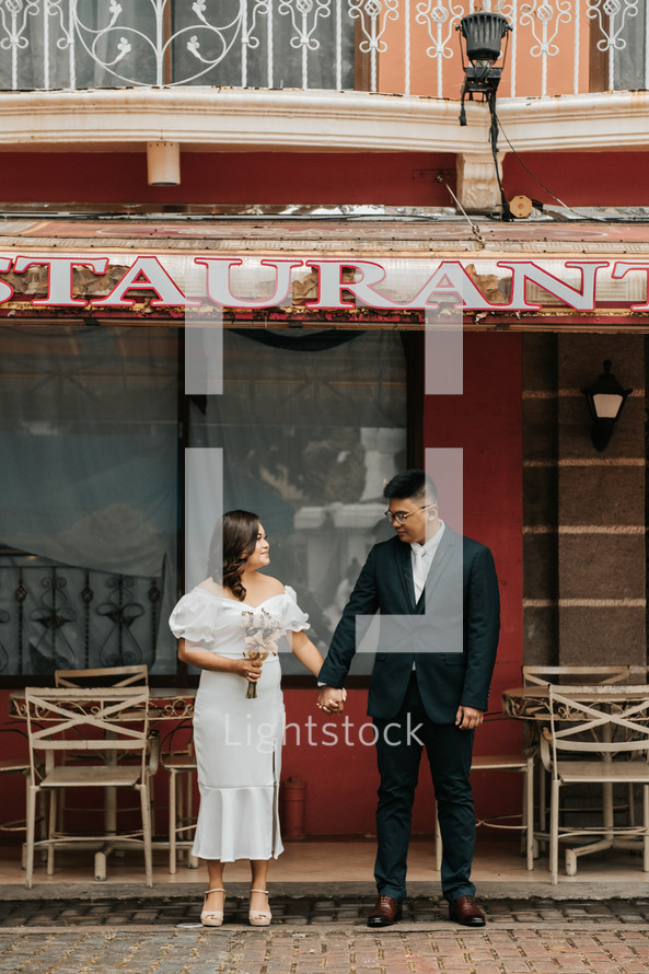 bride and groom standing in front of a restaurant 