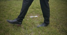 Sombre, sad young man in black suit walking in cinematic slow motion in cemetery through graveyard tombstones.