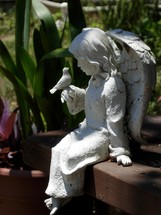 Feathered friends - A statue of a female angel and a little bird taking time to fellowship together in a garden.