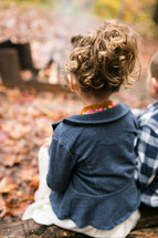 children sitting outdoors on a fall day 
