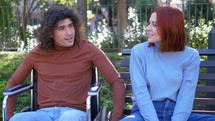 Man and woman having a conversation on a park bench, laughing and smiling. 