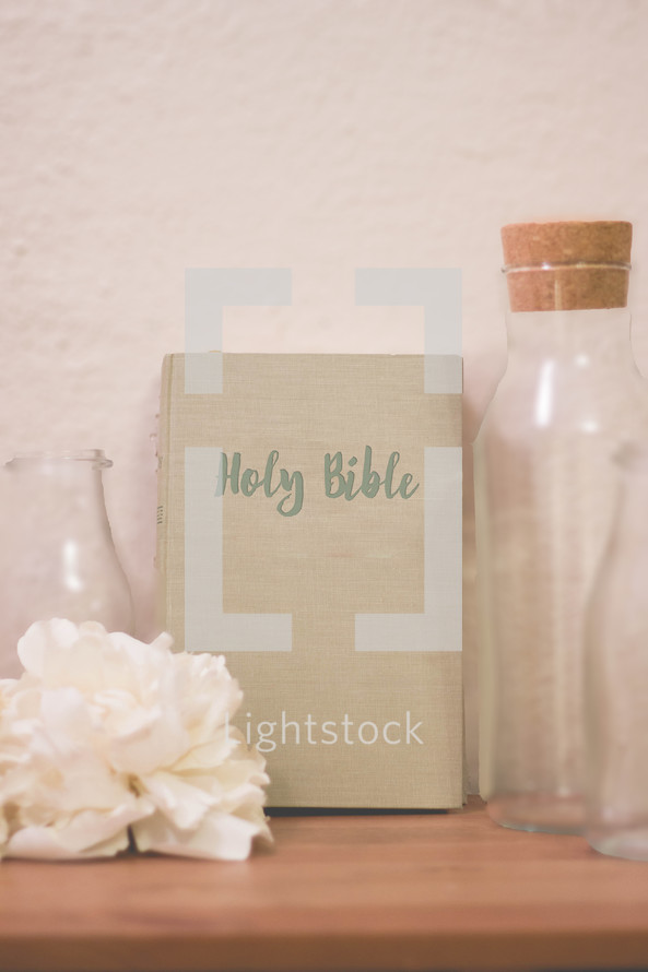 Holy Bible, flower, glass bottles, on a wood shelf 